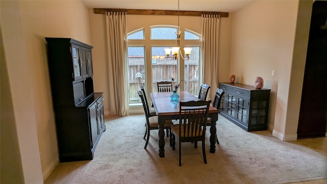 dining room with a notable chandelier, baseboards, and light carpet