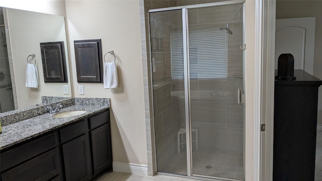 full bathroom with vanity, a shower stall, and baseboards