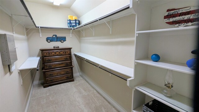 spacious closet with light colored carpet and vaulted ceiling