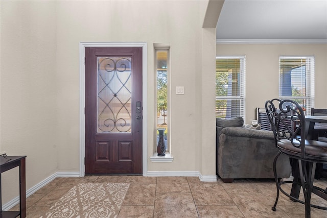 foyer entrance with light tile patterned floors, ornamental molding, and baseboards