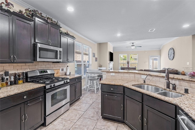 kitchen with a sink, open floor plan, appliances with stainless steel finishes, backsplash, and crown molding