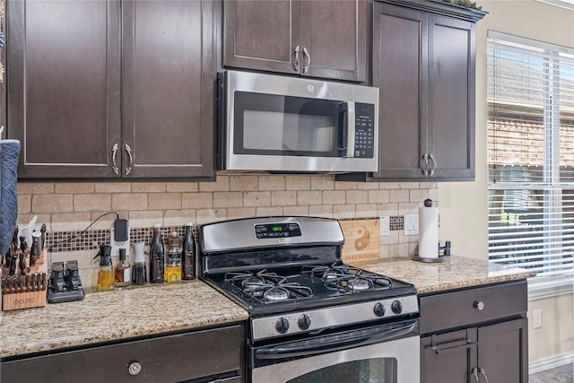 kitchen featuring light stone countertops, appliances with stainless steel finishes, backsplash, and dark brown cabinets