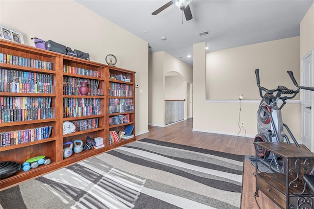 sitting room featuring arched walkways, ceiling fan, wood finished floors, visible vents, and an upstairs landing