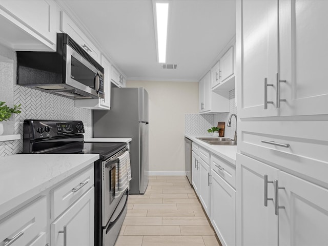 kitchen with stainless steel appliances, visible vents, wood tiled floor, white cabinetry, and a sink