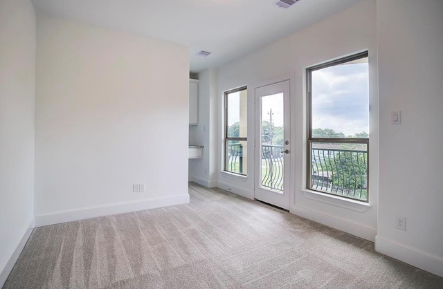 spare room featuring baseboards, visible vents, and light colored carpet