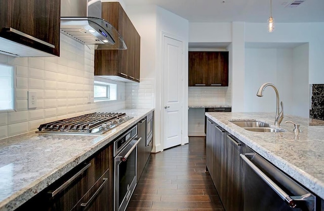 kitchen with dark wood-style floors, stainless steel appliances, dark brown cabinetry, a sink, and wall chimney exhaust hood