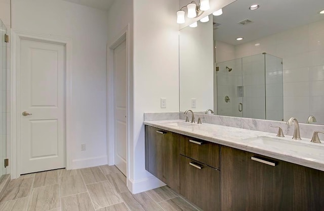 bathroom with double vanity, a stall shower, a sink, and visible vents