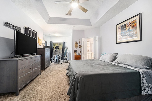 bedroom with light carpet, visible vents, a ceiling fan, a tray ceiling, and a textured ceiling