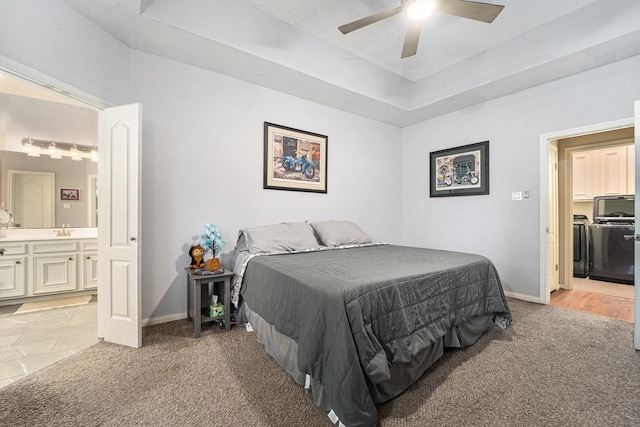 bedroom featuring a raised ceiling, light carpet, a sink, and baseboards