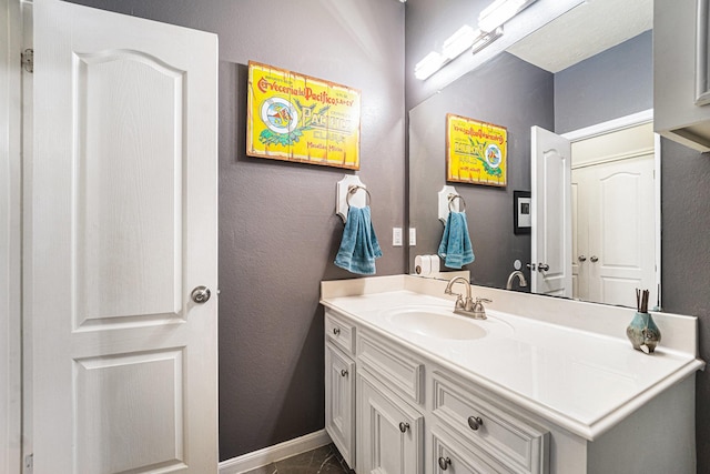 bathroom with a textured wall, baseboards, and vanity