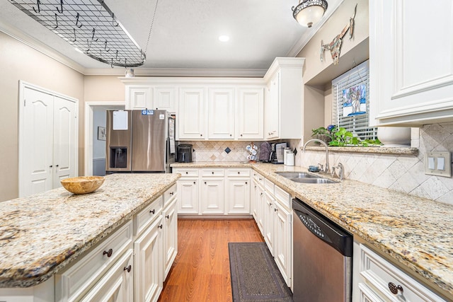 kitchen with appliances with stainless steel finishes, white cabinets, a sink, and ornamental molding