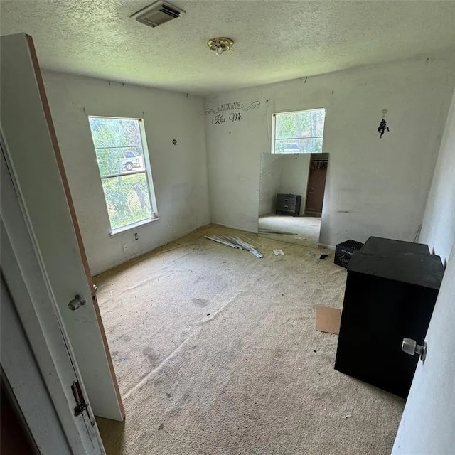 unfurnished bedroom with multiple windows, visible vents, and a textured ceiling