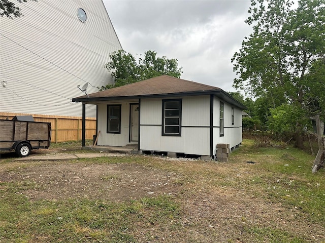back of house featuring fence and roof with shingles