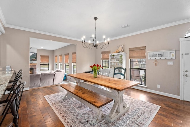 dining area with an inviting chandelier, a fireplace, baseboards, and dark wood finished floors