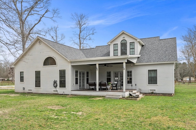 back of property featuring ceiling fan, a yard, and a shingled roof