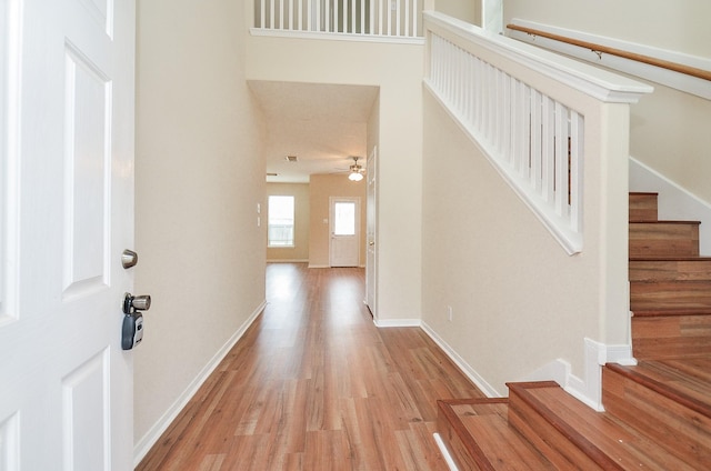 foyer featuring ceiling fan, stairway, baseboards, and wood finished floors