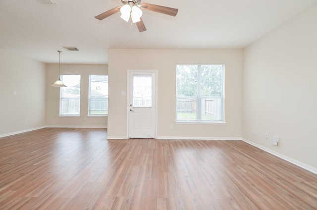 spare room featuring light wood finished floors, baseboards, visible vents, and a ceiling fan