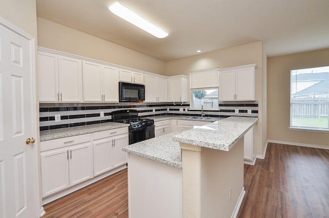 kitchen featuring decorative backsplash, white cabinets, a sink, a kitchen island, and black appliances