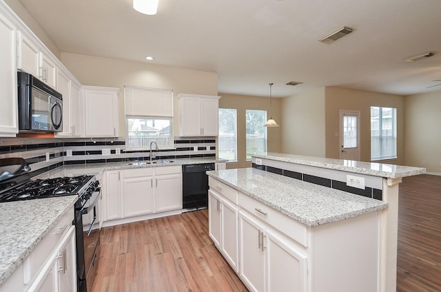 kitchen with light wood-type flooring, a center island, visible vents, and black appliances