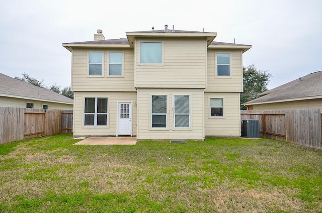 back of house with a fenced backyard, central AC, a yard, a chimney, and a patio area