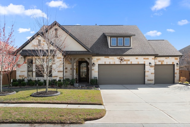 view of front of home featuring an attached garage, a shingled roof, stone siding, concrete driveway, and a front yard