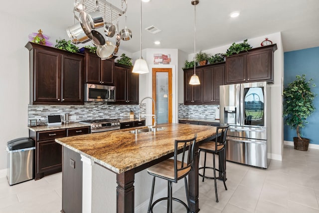 kitchen with light stone counters, dark brown cabinetry, a sink, visible vents, and appliances with stainless steel finishes