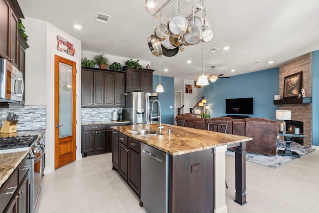 kitchen featuring light stone counters, a breakfast bar area, visible vents, appliances with stainless steel finishes, and a sink