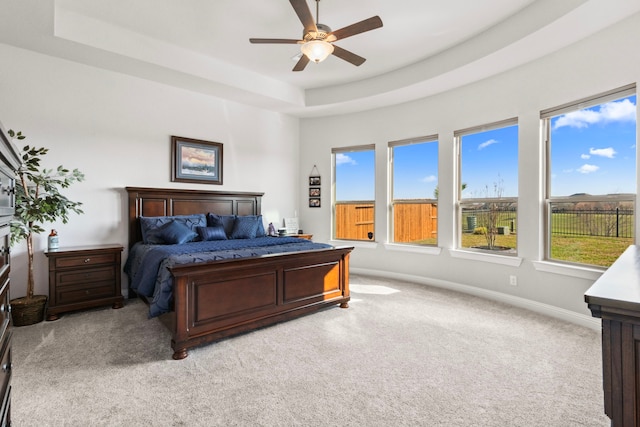 bedroom featuring ceiling fan, a raised ceiling, light colored carpet, and baseboards