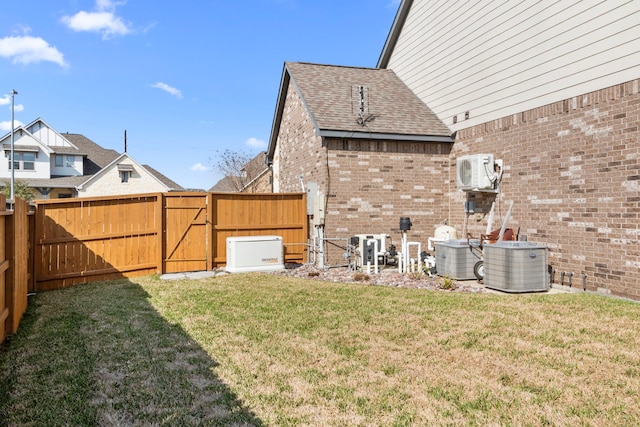 view of yard with ac unit, a fenced backyard, a gate, and cooling unit