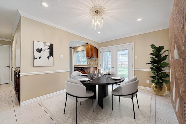 dining area featuring arched walkways, french doors, light tile patterned floors, and ornamental molding