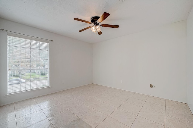 spare room with a ceiling fan, a textured ceiling, and light tile patterned floors