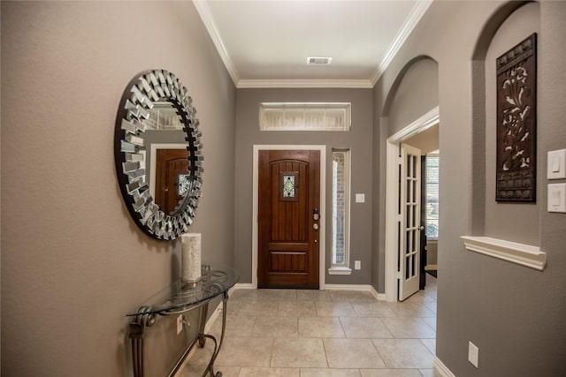 entryway featuring crown molding, light tile patterned floors, baseboards, and visible vents