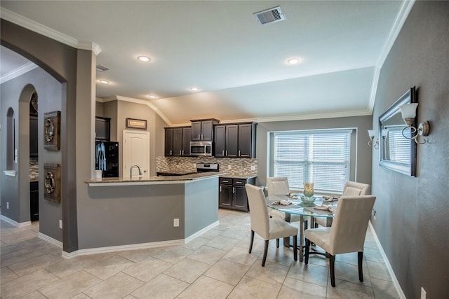 kitchen featuring visible vents, arched walkways, vaulted ceiling, appliances with stainless steel finishes, and tasteful backsplash