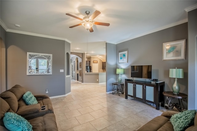 living area with baseboards, arched walkways, ornamental molding, and a ceiling fan