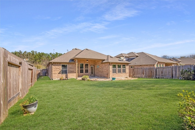 back of house with a lawn, roof with shingles, a fenced backyard, and brick siding