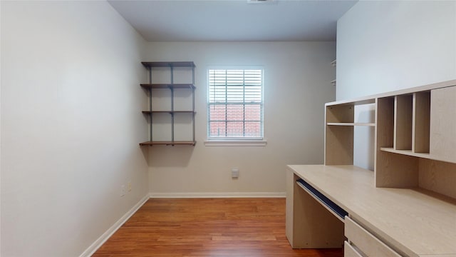 unfurnished office featuring light wood-type flooring and baseboards