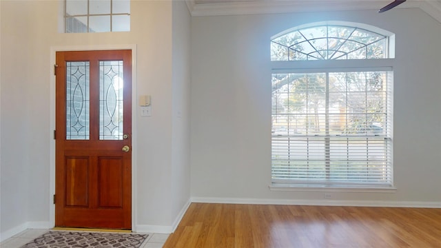 entryway featuring ornamental molding, plenty of natural light, light wood-style flooring, and baseboards