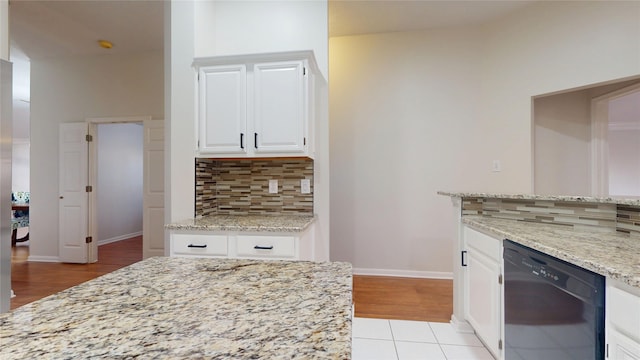 kitchen with light stone counters, decorative backsplash, white cabinets, dishwasher, and baseboards