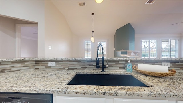 kitchen featuring light stone counters, visible vents, a sink, and backsplash