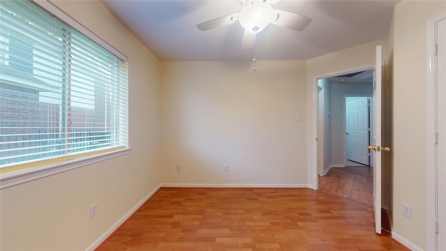 spare room with ceiling fan, light wood-style flooring, and baseboards