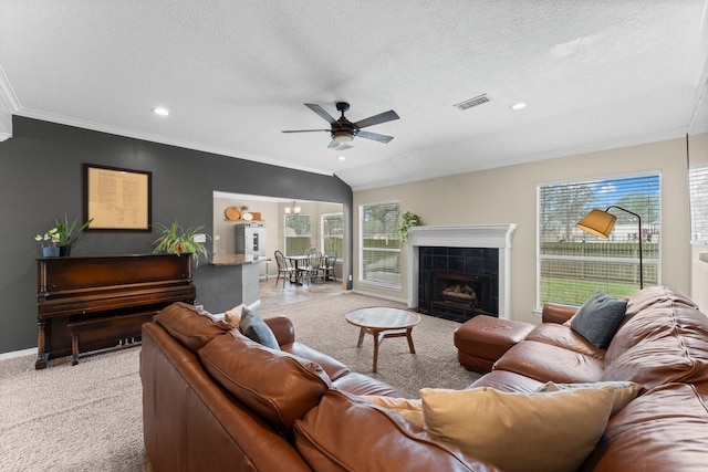 living room featuring ceiling fan, a textured ceiling, light carpet, a fireplace, and visible vents