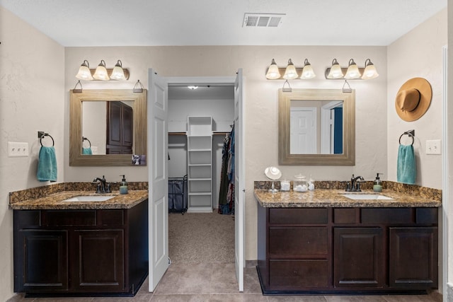 bathroom featuring visible vents, two vanities, and a sink