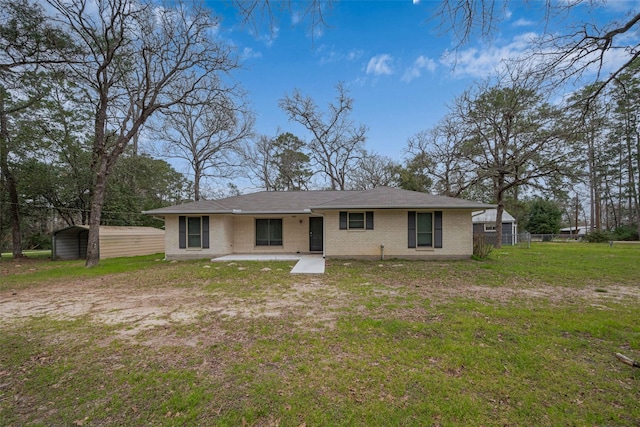 back of property featuring a carport, brick siding, a lawn, and fence