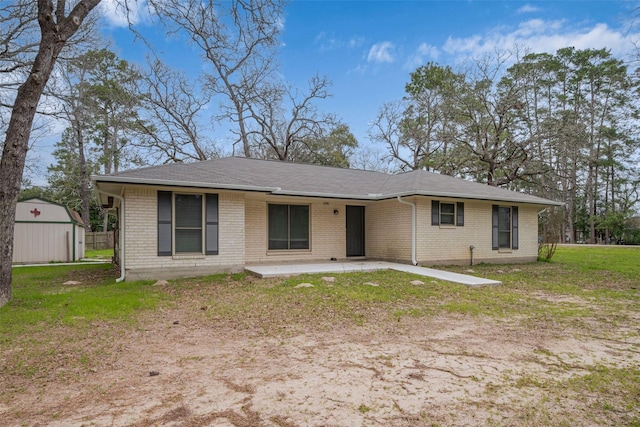 ranch-style house featuring an outbuilding, brick siding, a patio, a storage unit, and a front yard