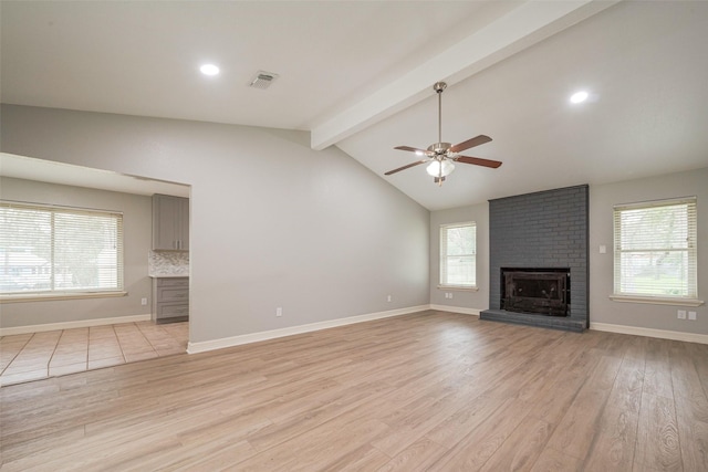 unfurnished living room with lofted ceiling with beams, visible vents, baseboards, a brick fireplace, and light wood finished floors