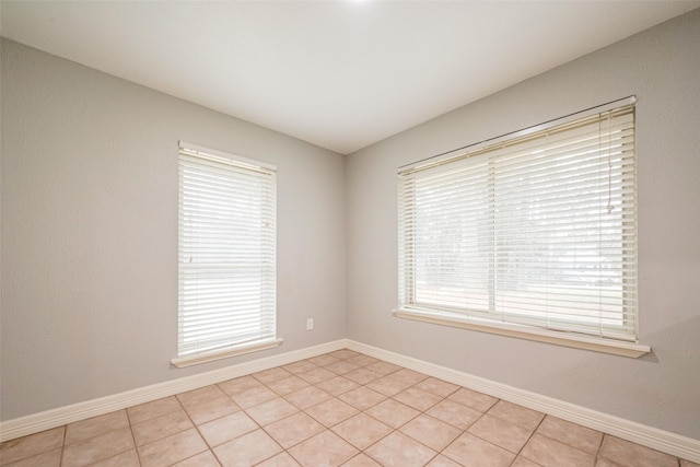 empty room with light tile patterned flooring and baseboards