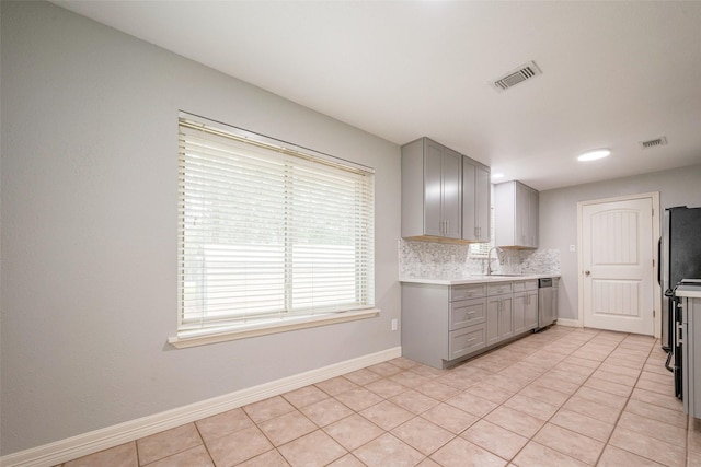 kitchen featuring gray cabinetry, a sink, visible vents, decorative backsplash, and dishwasher