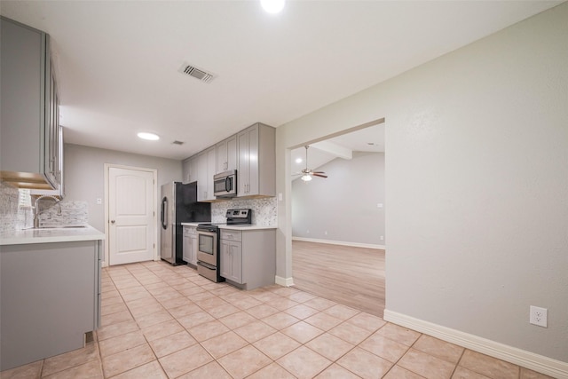 kitchen with appliances with stainless steel finishes, gray cabinets, visible vents, and a sink