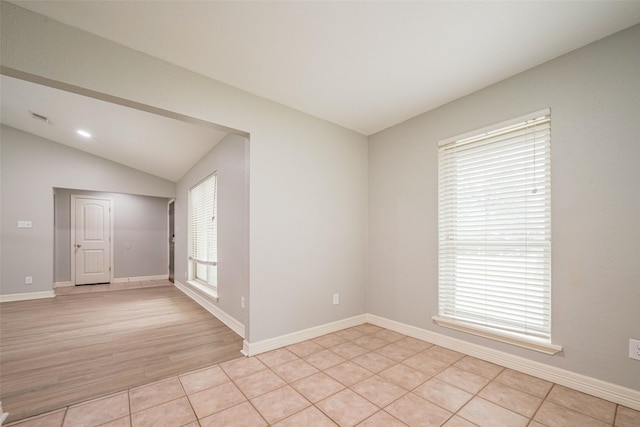 spare room with vaulted ceiling, light tile patterned flooring, and baseboards