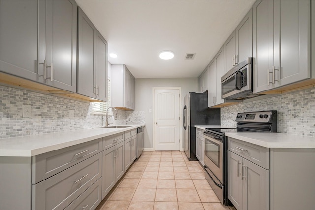 kitchen with visible vents, gray cabinetry, appliances with stainless steel finishes, light tile patterned flooring, and a sink